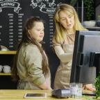 Café team members working together at the till, with one mentoring the other, representing inclusive employment practices and the importance of promoting authentic restaurant brand values.