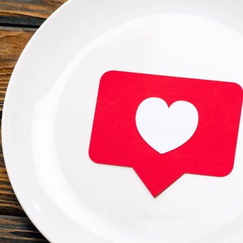 Social media like icon with a heart placed on a white plate, symbolising the connection between digital engagement and customer experience in the hospitality industry.