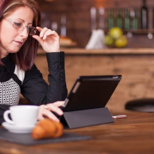 Hospitality business owner reviewing SEO reports on a tablet in a café, concerned about why their SEO isn’t driving results.