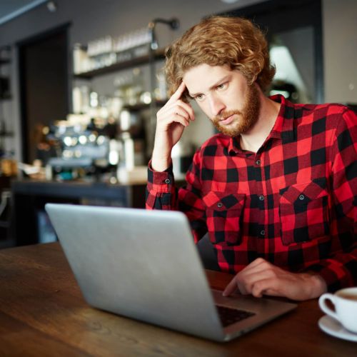 Man looking concerned at laptop in café, searching for copyright claim help for image use