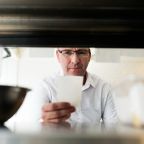 Executive chef inspecting a docket slip under a kitchen pass
